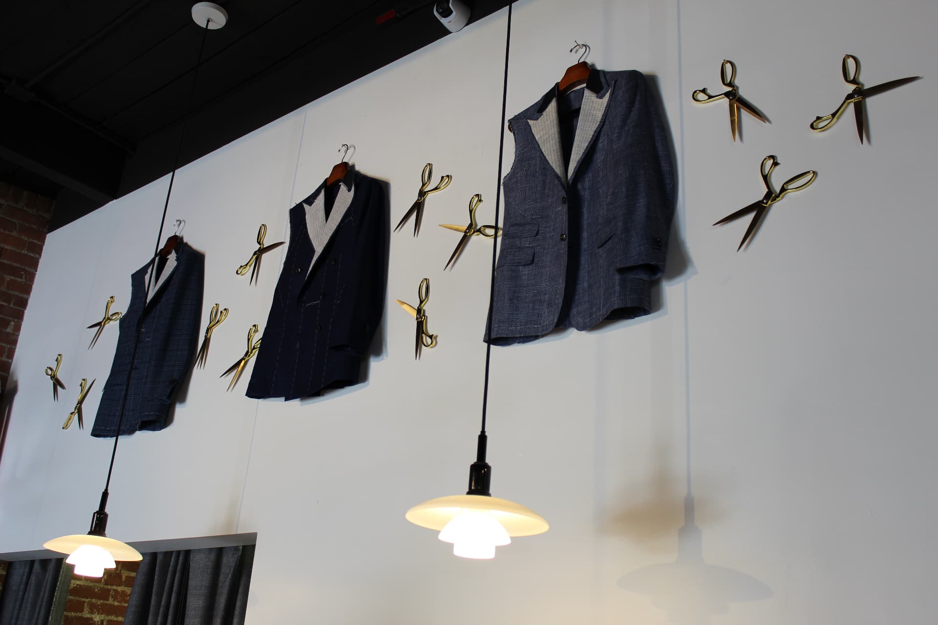Tailored jackets displayed among brass shears at Marc Allen
