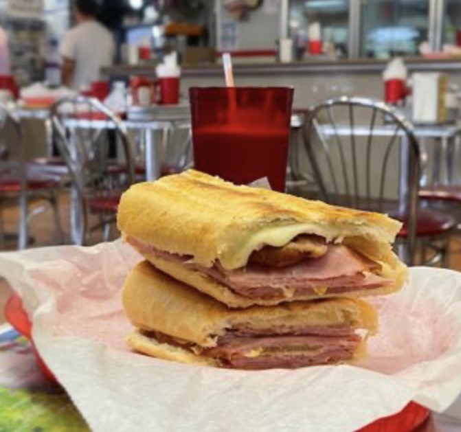 Stacked Cuban sandwich at Enriqueta's with a red cafeteria cup in the background