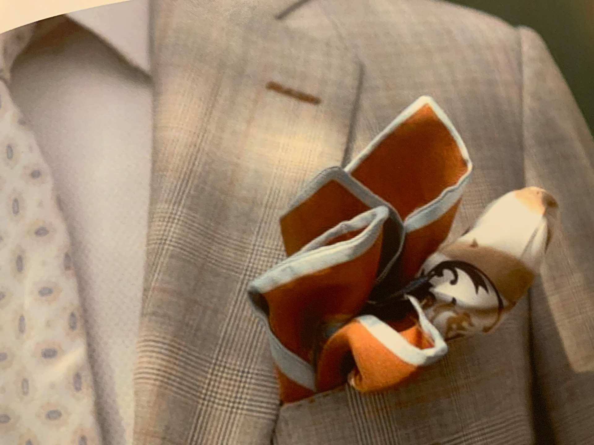 Rust, cream and blue silk pocket square arranged in a checked jacket