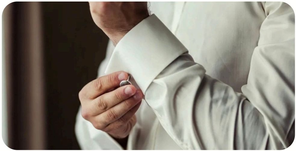 A cufflink being fastened on a white shirt cuff